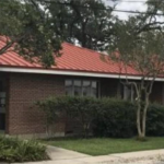Foundation shrubs and trimmed crape myrtles along a brick building after shrub removal in Marrero, LA