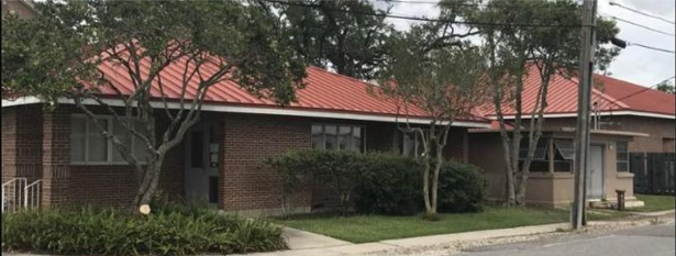 Foundation shrubs and trimmed crape myrtles along a brick building after shrub removal in Marrero, LA